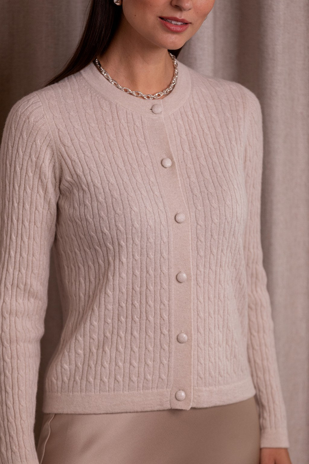 Lähikuva kashmirista valmistetusta ohuesta palmikkoneuletakista, sävyssä latte