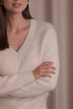 Lähikuva kermanvärisestä v-aukollisesta alpakkasekoiteneuleesta