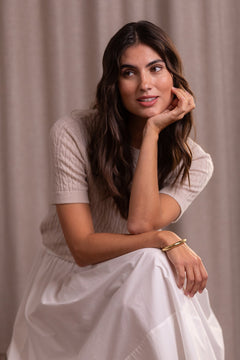 Nainen, jonka päällä Original Storyn palmikkoneule, joka valmistettu kashmirista. Sävyssä latte.