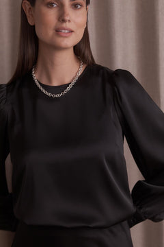 Lähikuva Original Storyn mustasta pitkähihaisesta satiinipaidasta puhvihihoilla.